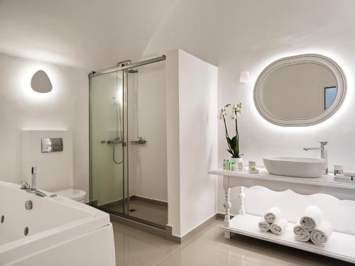 a white bathroom with a shower and a sink at Katikies Santorini - The Leading Hotels Of The World in Oia