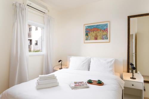 a bedroom with a white bed and a window at Gordon Seaside 4BDR apt in TLV in Tel Aviv