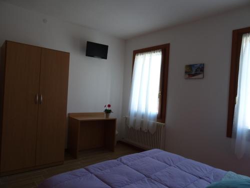 a bedroom with a bed and a dresser and two windows at B&B Giardino di Ro in Cazzago di Pianiga