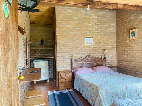 een slaapkamer met een bed en een bakstenen muur bij Chalé buraco do tatu in Conceição da Ibitipoca