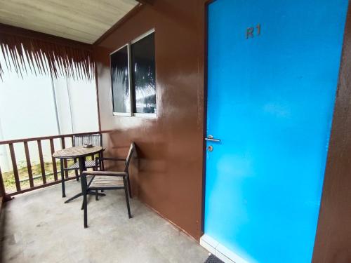 une porte bleue avec une table et une chaise sur un balcon dans l'établissement Tiongman Scubadive & Lodge, à l'Île Tioman