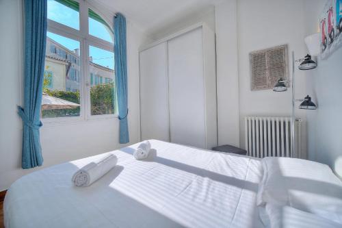 une chambre blanche avec un lit avec deux serviettes dessus dans l'établissement IMMOGROOM -Terrace with garden - Quiet - Air-conditioner, à Cannes