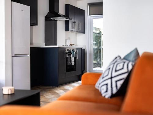 a living room with an orange couch and a kitchen at Isaacs View - Ground Floor Apartment in Cleethorpes
