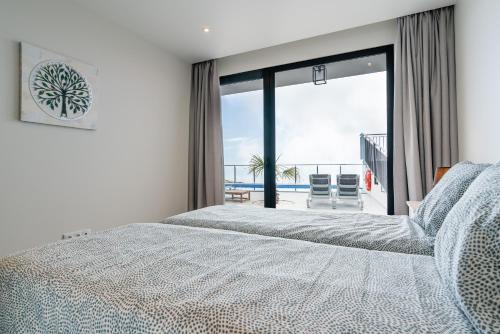 a bedroom with a bed and a view of the ocean at Casa Bella Vista - Calheta in Arco da Calheta