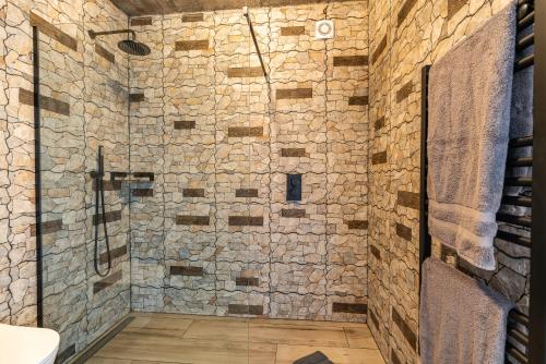 a bathroom with a shower with a stone wall at Casa Bella Vista - Calheta in Arco da Calheta