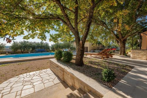 a park with a bench and trees and a pool at Holiday home Apios in Benkovac