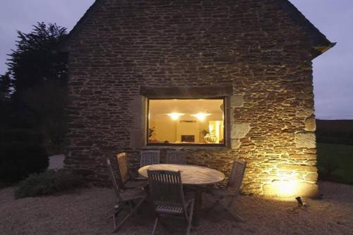- un bâtiment en pierre avec une table, des chaises et un miroir dans l'établissement La Longère de Sophie, à Plouénan
