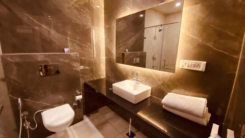 W łazience znajduje się umywalka, toaleta i lustro. w obiekcie Hotel Amar Palace w mieście Ambala