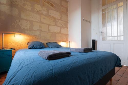 een slaapkamer met een bed met blauwe lakens en kussens bij Maison spacieuse avec Jardin et Garage in Bordeaux