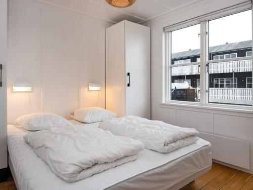 a white bedroom with two beds and a window at Holiday home Ebeltoft CCXVII in Ebeltoft
