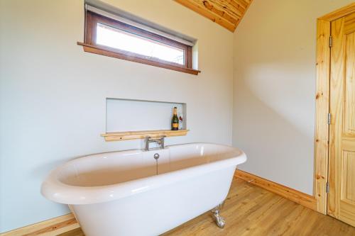 eine weiße Badewanne im Bad mit Fenster in der Unterkunft Roe Deer Lodge with Hot Tub in Cray