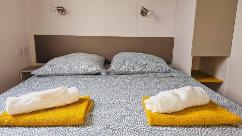 a bed with two pillows on top of it at Joli Mobil home N°11, 4ch tout confort et spacieux in Gastes