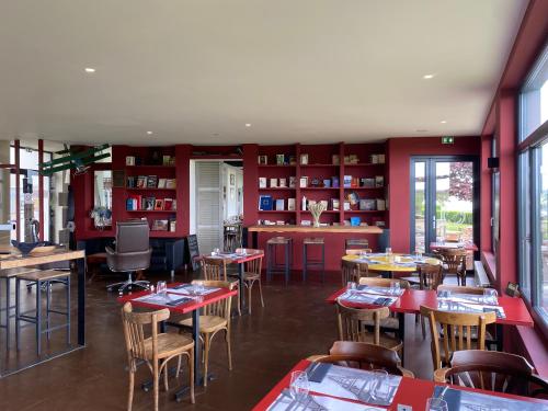 a restaurant with tables and chairs in a room at Logis Hôtel & Restaurant de l'Aérodrome de la Baie de Somme in Buigny-Saint-Maclou
