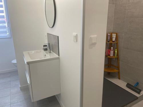 Baño blanco con lavabo y espejo en T2 stylé/calme et confortable en Arcachón