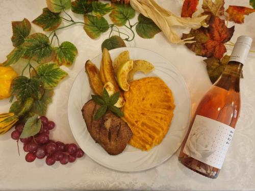 a plate of food with meat and french fries and a bottle of wine at Boglárka Panzió - Étterem in Mezőkövesd