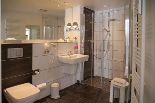 a bathroom with a sink and a shower and a toilet at Hotel am Nikolaiort in Osnabrück