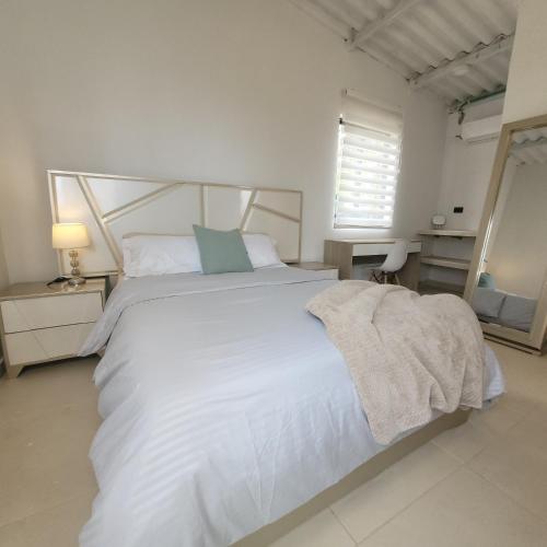 a bedroom with a large white bed and a mirror at Casa Suite Palmar del viento FRENTE, FRENTE AL MAR by Amauna in Moñitos