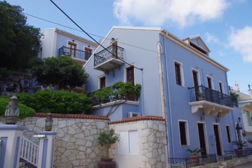 a white building with balconies and a stone wall at Faros Suites (Adults Only) in Fiskardho