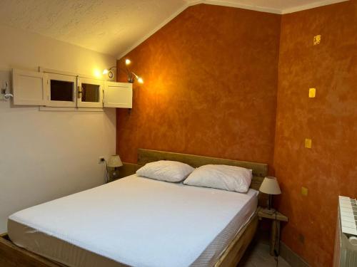 a bedroom with a bed with white sheets and orange walls at La tana club Suite Oro & Argento in Serina