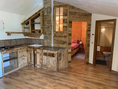 a kitchen with wooden cabinets and a room with a toilet at Paradise La Tana in Serina