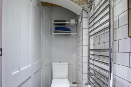 a bathroom with a toilet in a white tiled wall at Walcot Apartment in Bath