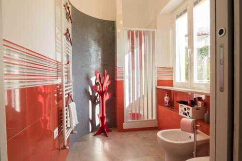 a bathroom with a white toilet and a red wall at Casa Linda, a due passi dal mare in Numana