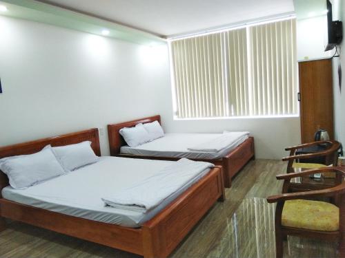 two beds in a room with a window at Khách sạn Gia Nghiêm in Ấp Trà Kha