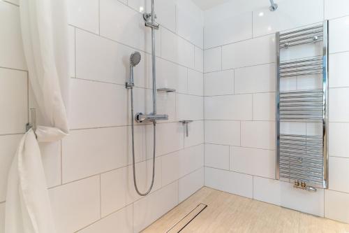 a shower in a bathroom with white tiles at Hus op de Dün Storchennest in Sankt Peter-Ording