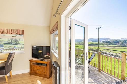 a room with a desk and a television and a balcony at Pine Marten Lodge with Hot Tub in Cray