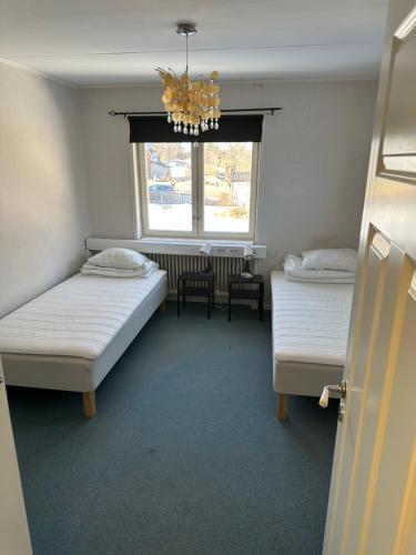 a room with two beds and a window and a chandelier at Lärkan 21 Tvisegatan 24 in Borlänge