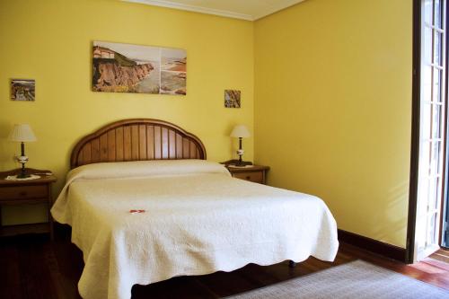 a bedroom with a white bed with yellow walls at Pension Getariano in Getaria