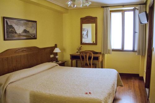 a bedroom with a bed and a desk and a window at Pension Getariano in Getaria
