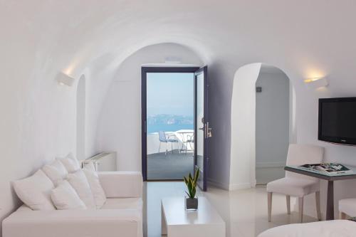 un salon blanc avec un canapé blanc et une table dans l'établissement Katikies Chromata Santorini - The Leading Hotels of the World, à Imerovigli