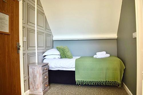 a small bedroom with a bed with a green blanket at Blakeney House in Blakeney