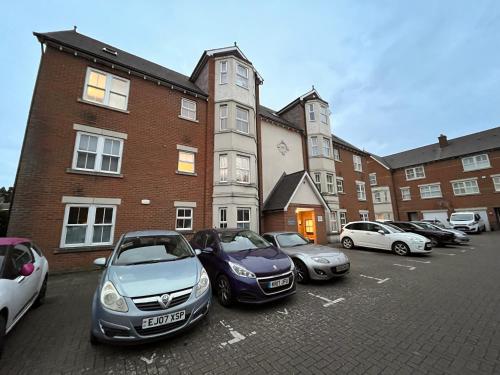 a row of cars parked in a parking lot in front of a building at Harrietsham House in Kent
