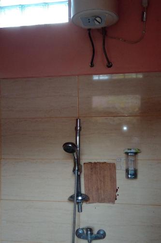 a shower in a room with a wooden wall at Villa Adhi Rajasa in Penebel