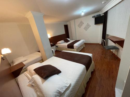 Habitación de hotel con 2 camas y escritorio en Gran Hotel Napoleón, en Ambato