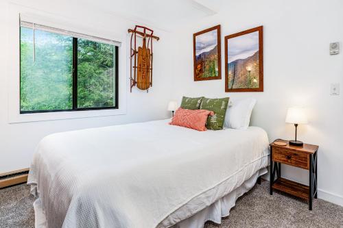 a white bedroom with a bed and two windows at Sugar Mountain Serenity in Banner Elk