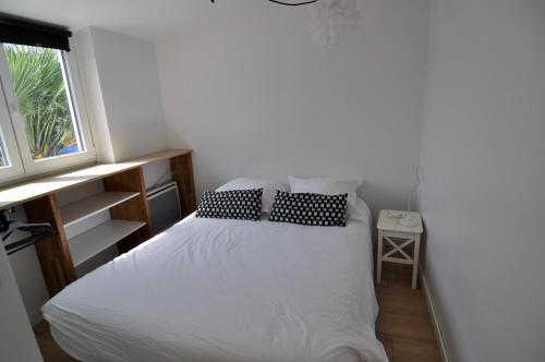 a bedroom with a white bed with pillows and a window at Petite maison cosy-9mn à pied gare, 5 mn plage ! in Pornichet