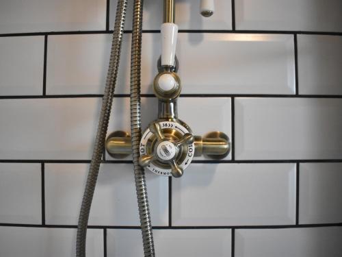 une salle de bains avec un tuyau fixé à un mur dans l'établissement Church View Cottage, à Ashbourne
