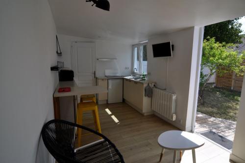 une petite cuisine avec une table et des chaises dans une pièce dans l'établissement Petite maisonnette 9mn à pied gare, 5 mn plage !, à Pornichet