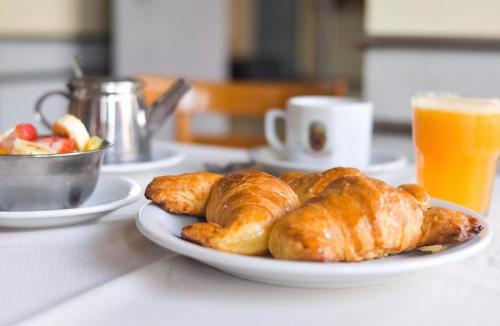 a plate of croissants and a bowl of fruit and orange juice at Hotel La Perla in Buenos Aires