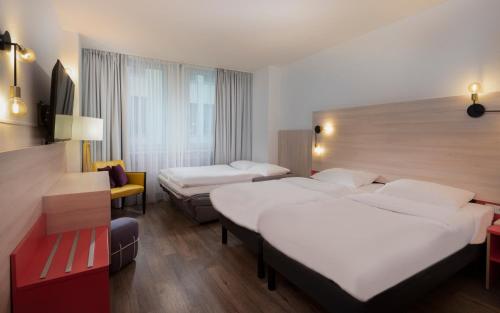 a hotel room with three beds and a tv at greet Berlin Alexanderplatz in Berlin