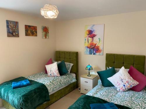 a bedroom with two beds and a table with a lamp at Exquisite Modern Homely 2 Bed Apartment with On-street Parking, Super Fast WIFI & 5 mins drive to Science & Business Parks in Cambridge