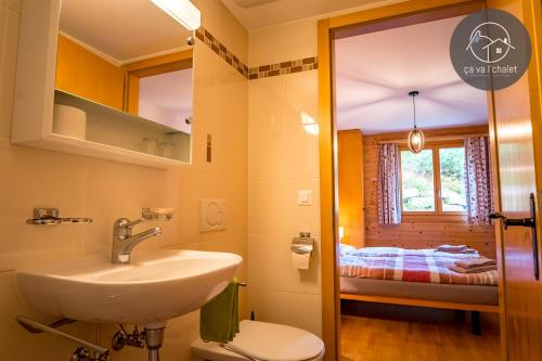 a bathroom with a sink and a toilet and a bedroom at RHODOS, Confort et Espace in Ovronnaz