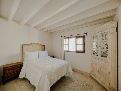 a white bedroom with a bed and a window at Casa Chiquitos in San Miguel de Allende