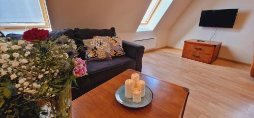 uma sala de estar com um sofá e uma mesa com flores em Apartamenty przy Promenadzie em Mikolajki