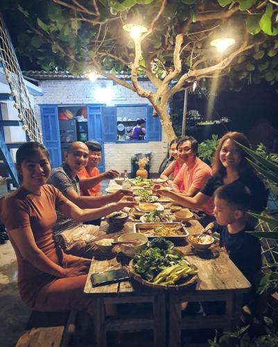 a group of people sitting around a table with food at nhà Ba cơm Má in Phương Phi