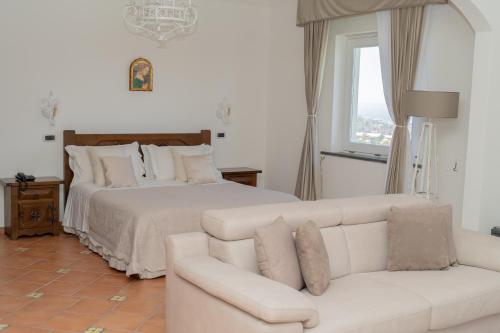 a white bedroom with a bed and a couch at Villa Palmentiello in SantʼAntonio Abate