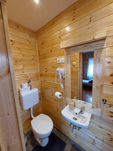 a log cabin bathroom with a toilet and a sink at Fenyőfa vendégház in Szilvásvárad